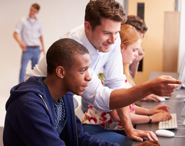 High school teacher showing student how to use a database