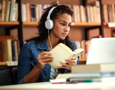 Researcher reading laterally, checking both her laptop and a book