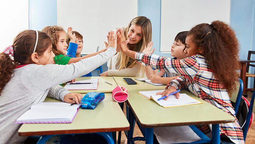 Teacher and young students celebrating accomplishment with group high-five