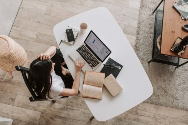 Female high school student hard at work, with laptop and book on desk